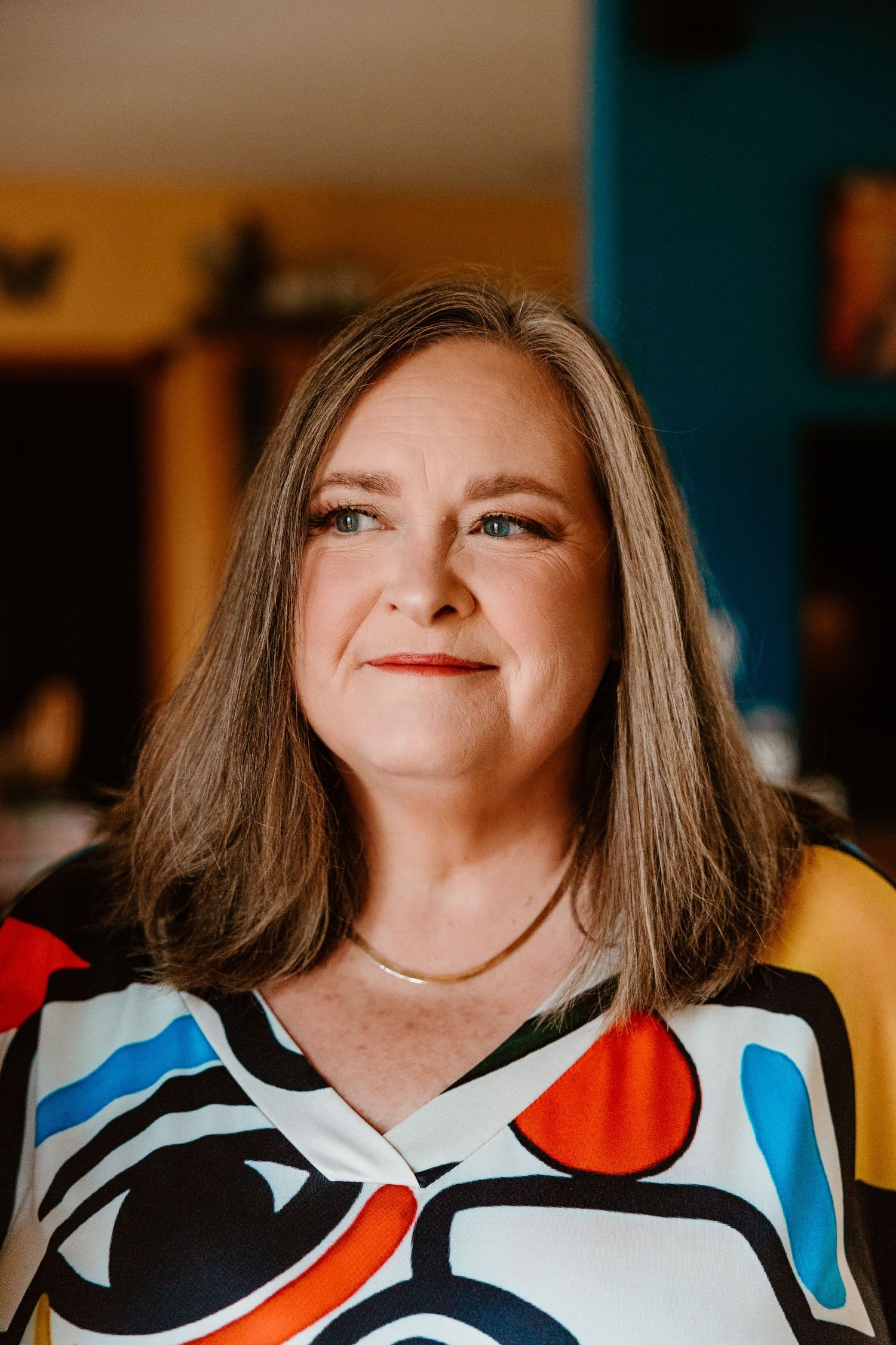 Person wearing colorful geometric patterned top in warm indoor lighting.