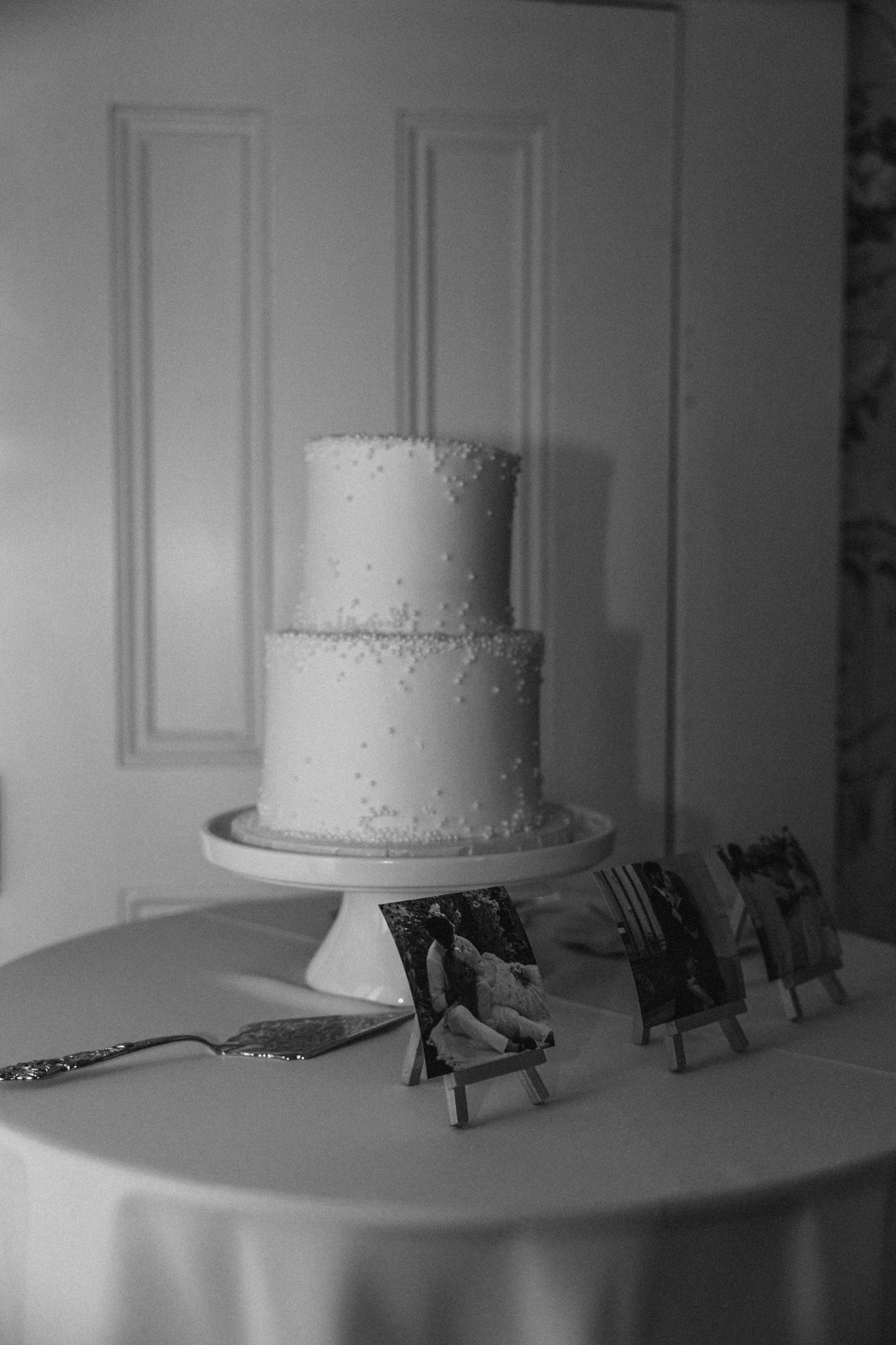 White tiered wedding cake displayed on a table with decorative utensils.