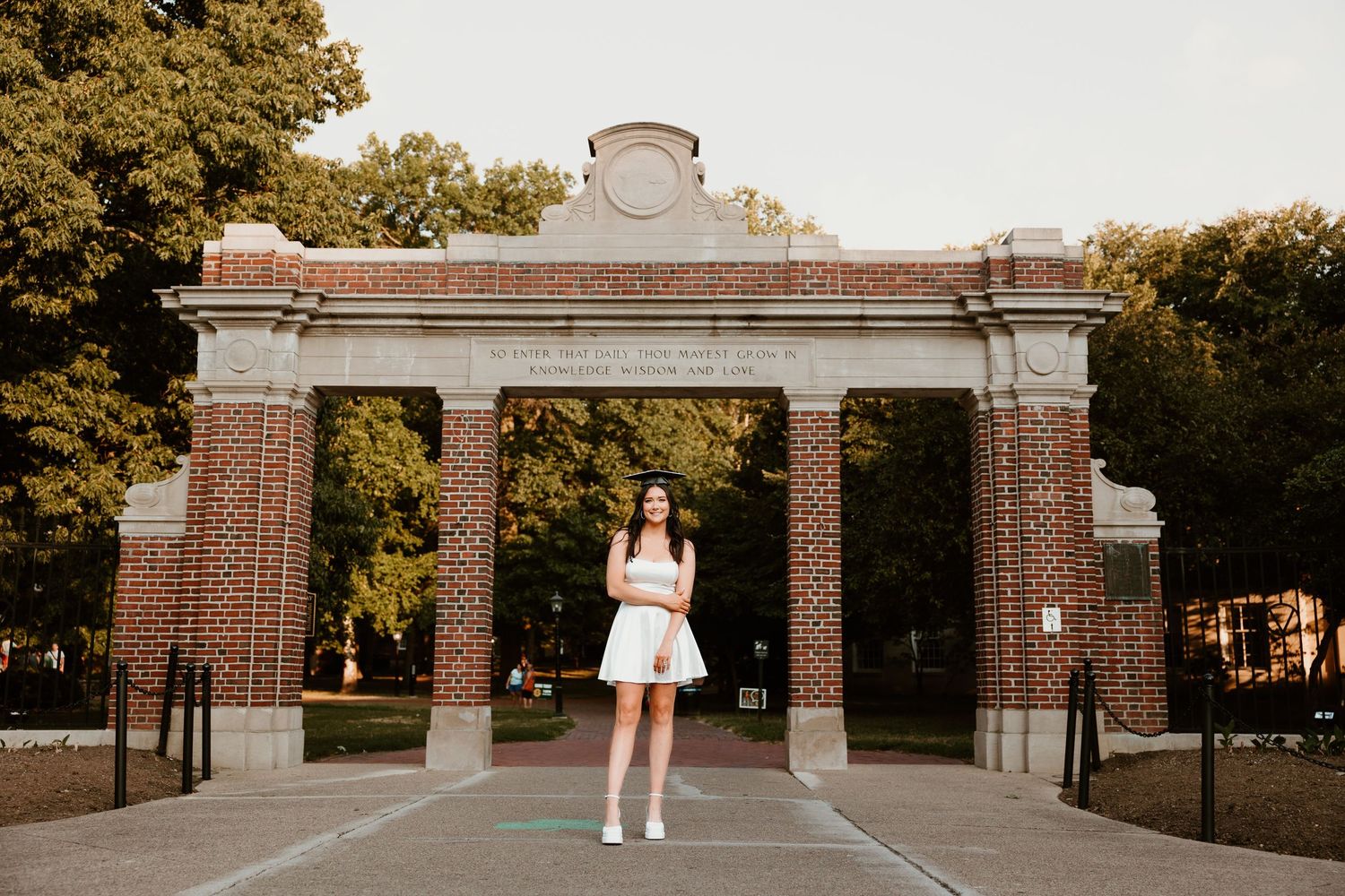 Brick archway entrance to a school or university campus at sunset.