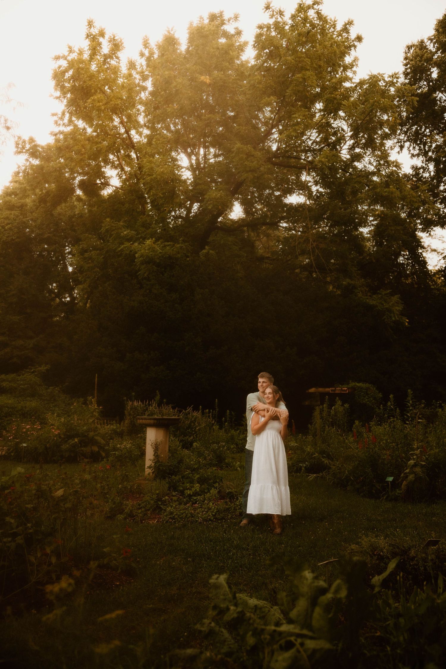 A figure in white stands gracefully in a sunlit field during golden hour.