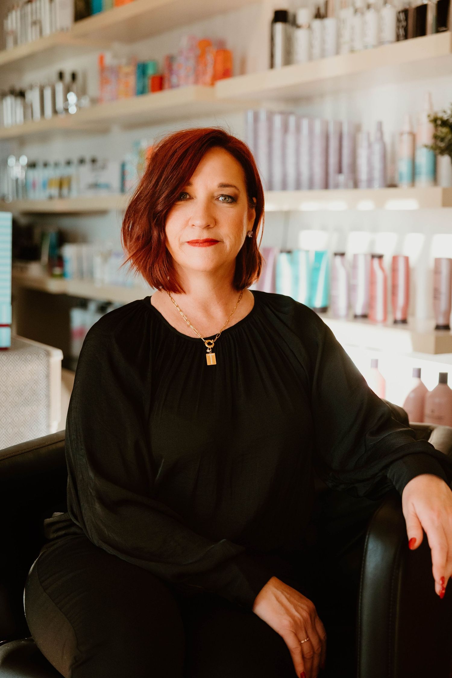Professional salon portrait with beauty product shelves in background.