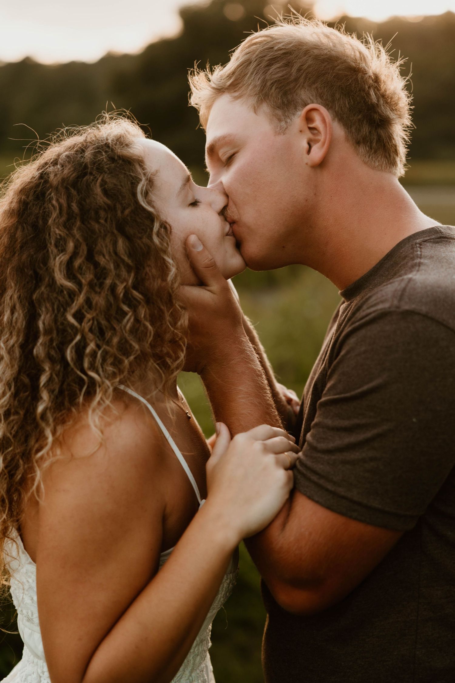 Intimate close-up of couple sharing tender moment in warm sunset lighting.