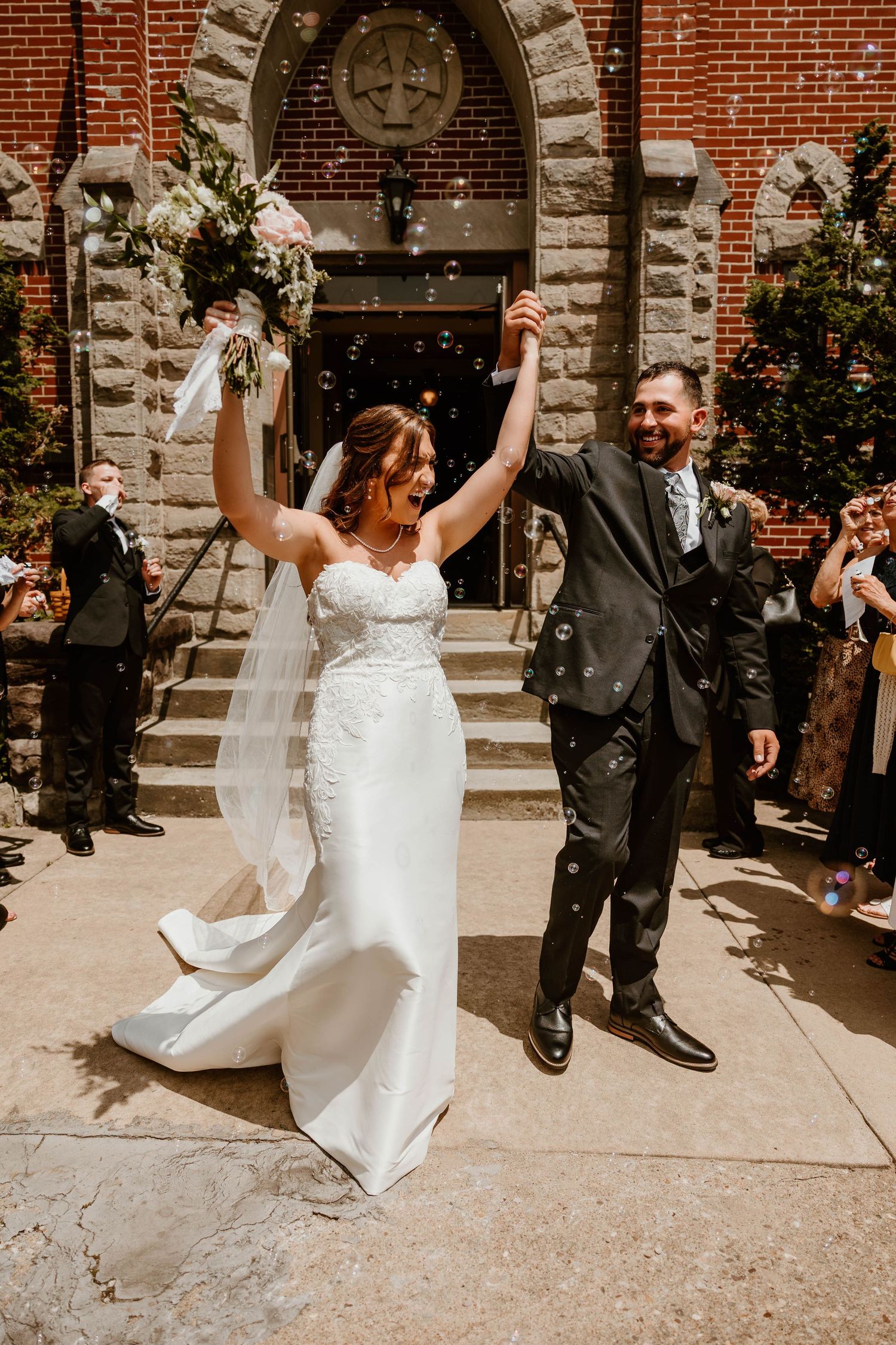 Newlyweds celebrate with confetti outside a historic brick church building.