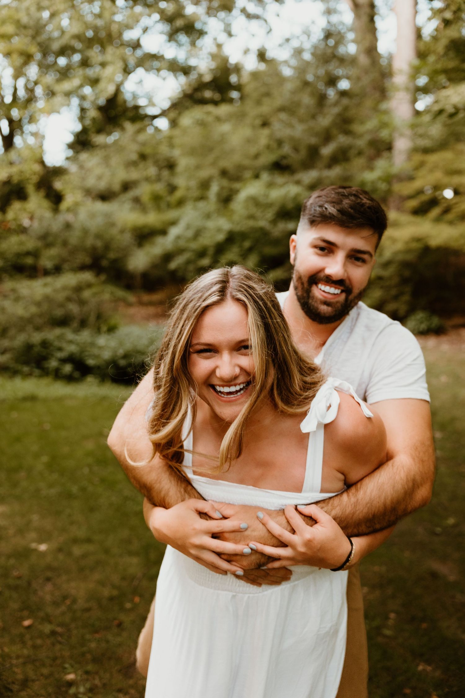A joyful couple laughs together in a garden setting.