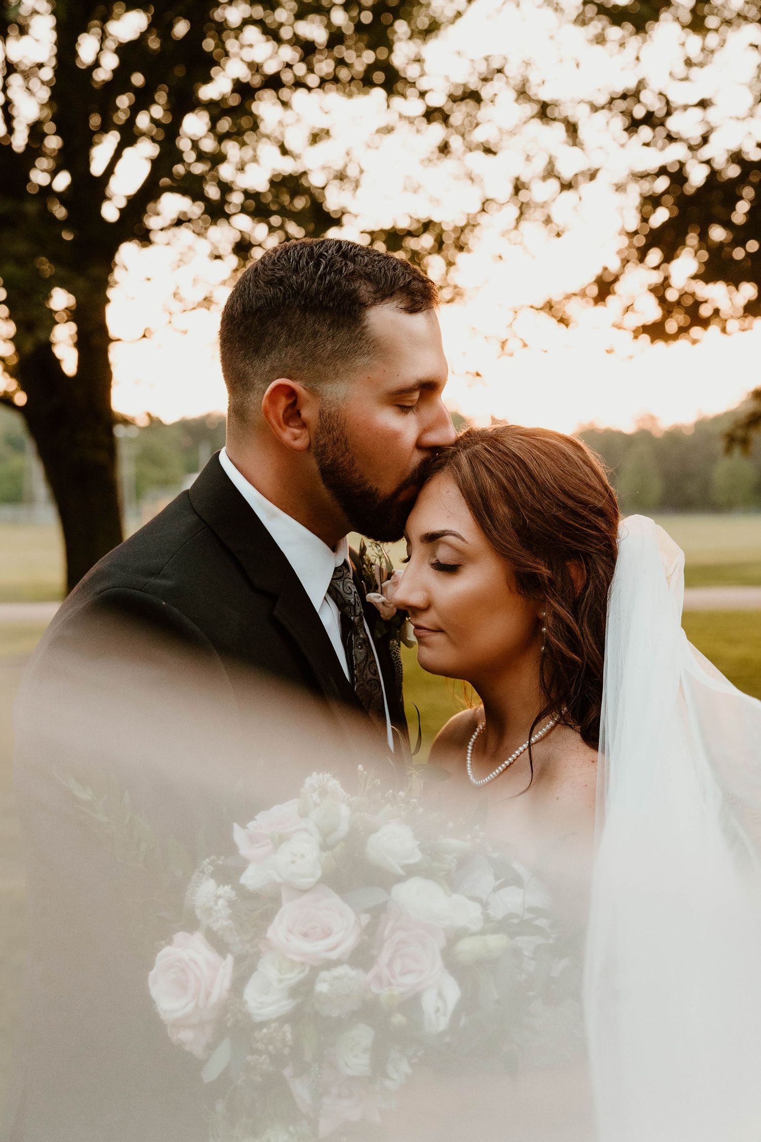 An intimate wedding portrait captured during golden hour with soft bokeh and roses.