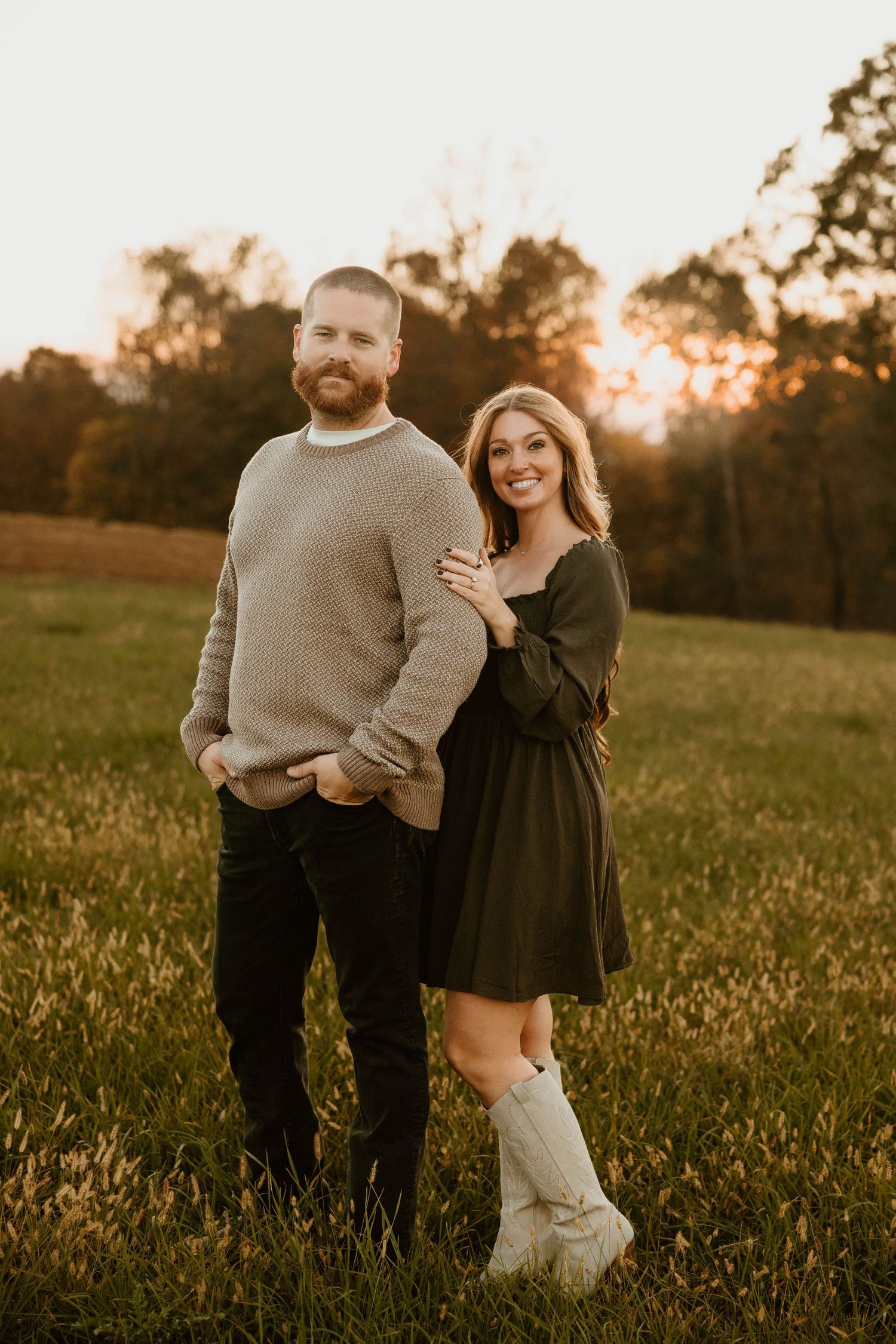 Couple playing and laughing together in a sunlit field during golden hour.