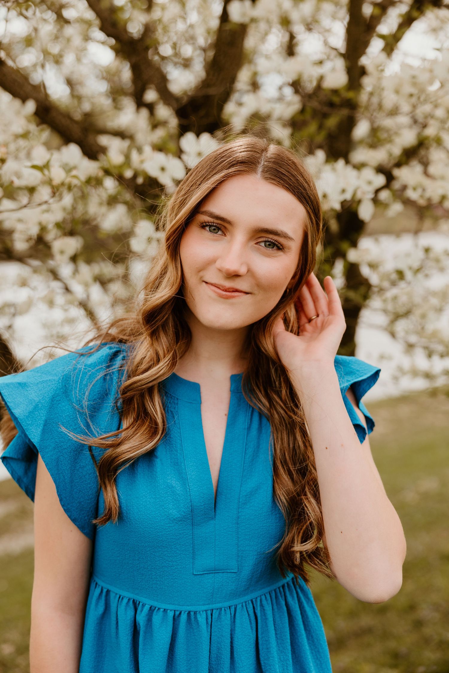 Portrait series in a spring garden with cherry blossoms and a bright blue flutter sleeve dress.