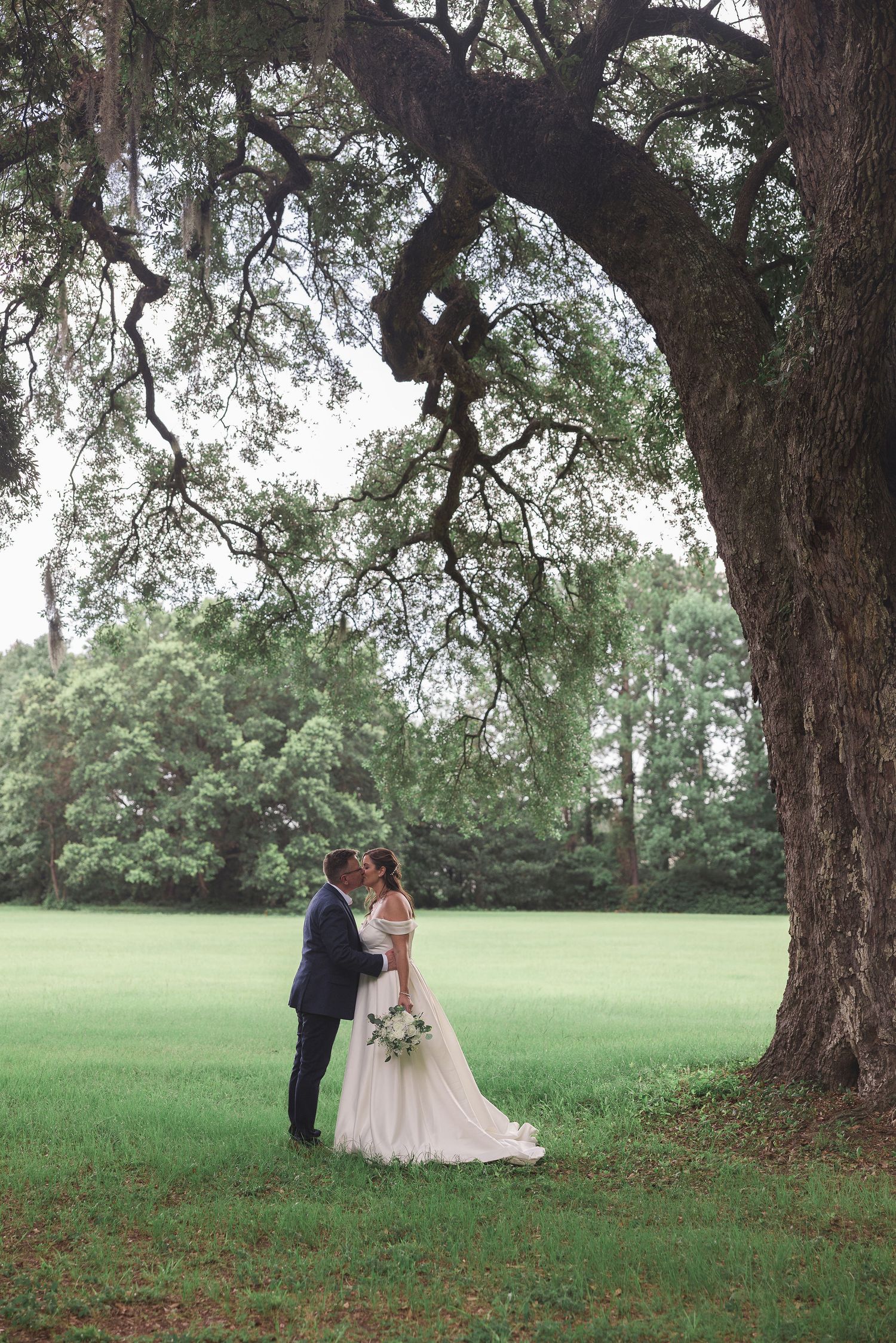 Bride and groom on wedding day at serene park in Charleston, SC. under a live oak tree celebrating the start of their great new journey.