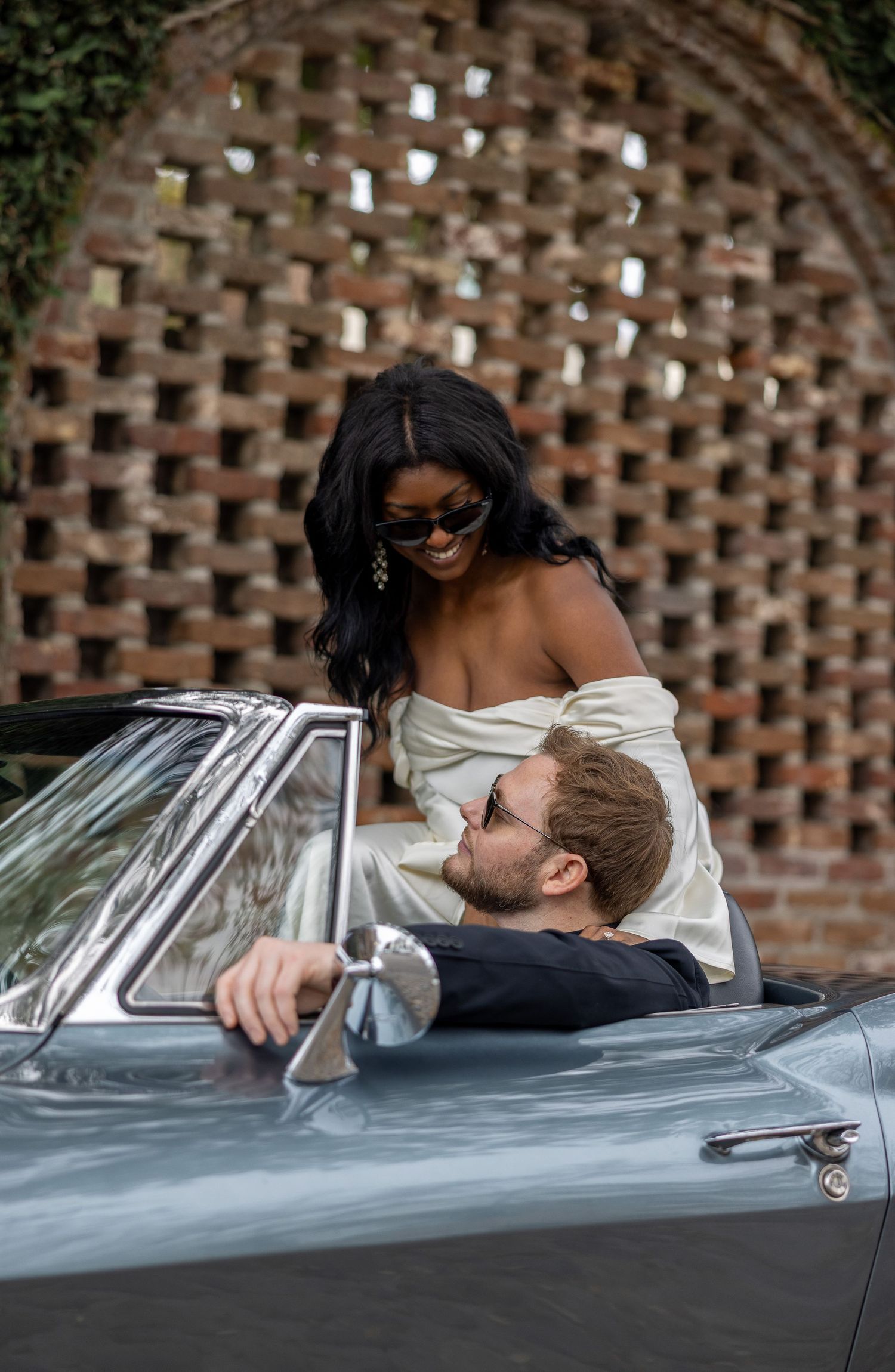 Engaged couple at the start of a new journey in a 66 Corvette on the cobblestone streets of Charleston, SC. in a warm embrace.