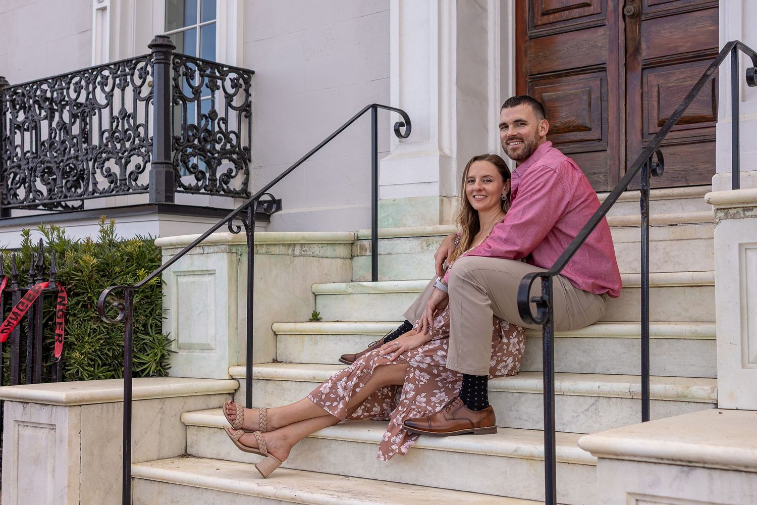 Engaged couple sharing a moment on one of the stately homes int he historic district of Charleston, SC sharing a warm embrace.