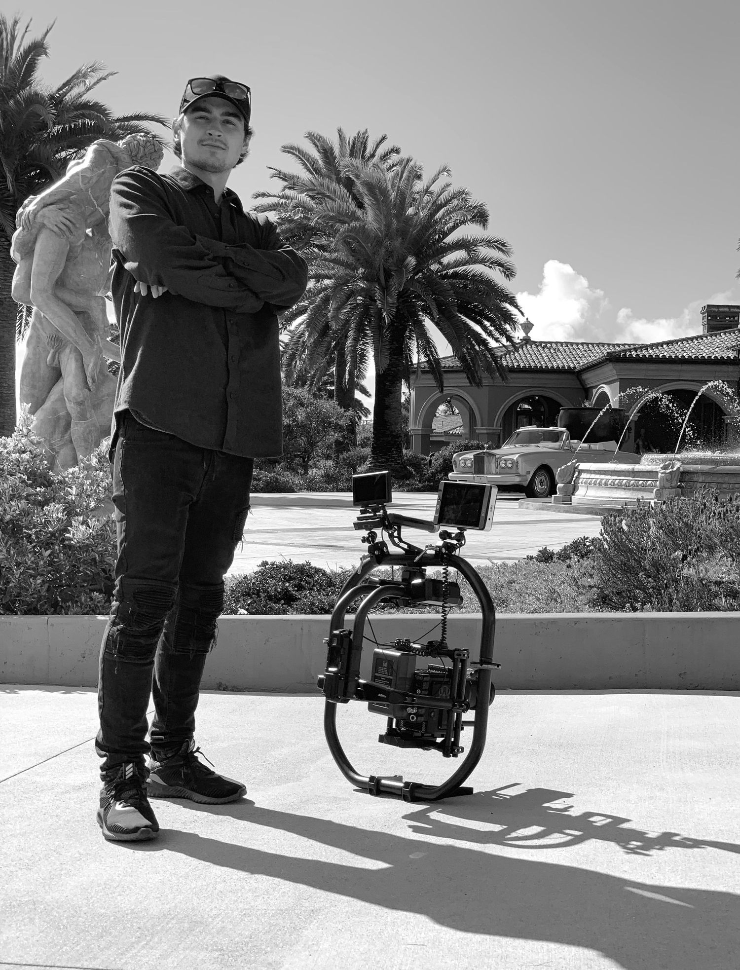 Man with video camera posing in front of luxury estate