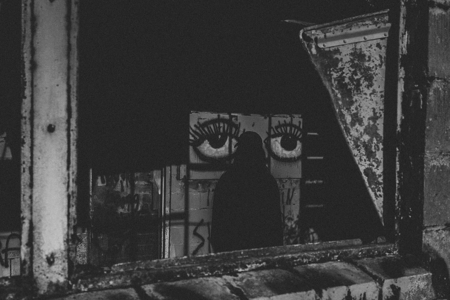 Black and white abstract photo of person in front of graffiti
