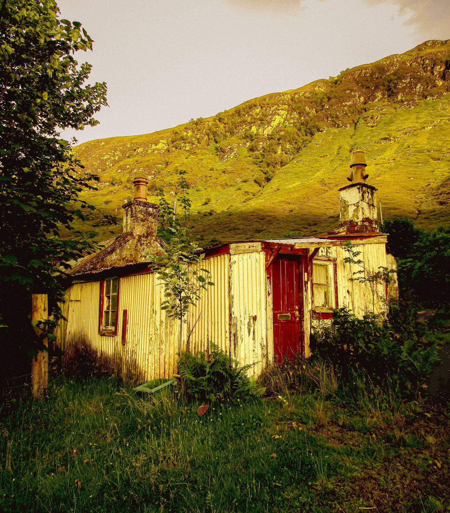 Fine art landscape of old corrugated metal cottage and red door with sunlit mountain, framed wall art prints and downloads,