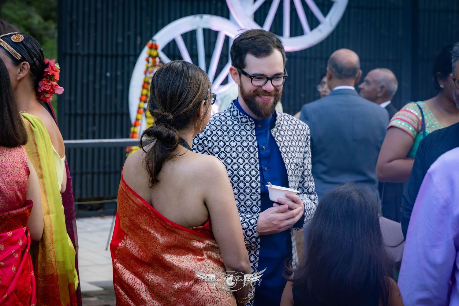 Guests mingling at an outdoor event wearing traditional Indian and western fusion attire.