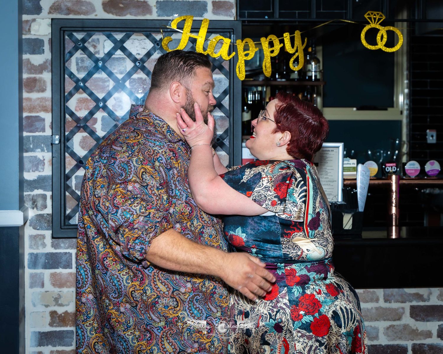 Couple sharing a playful moment in front of a decorated storefront.