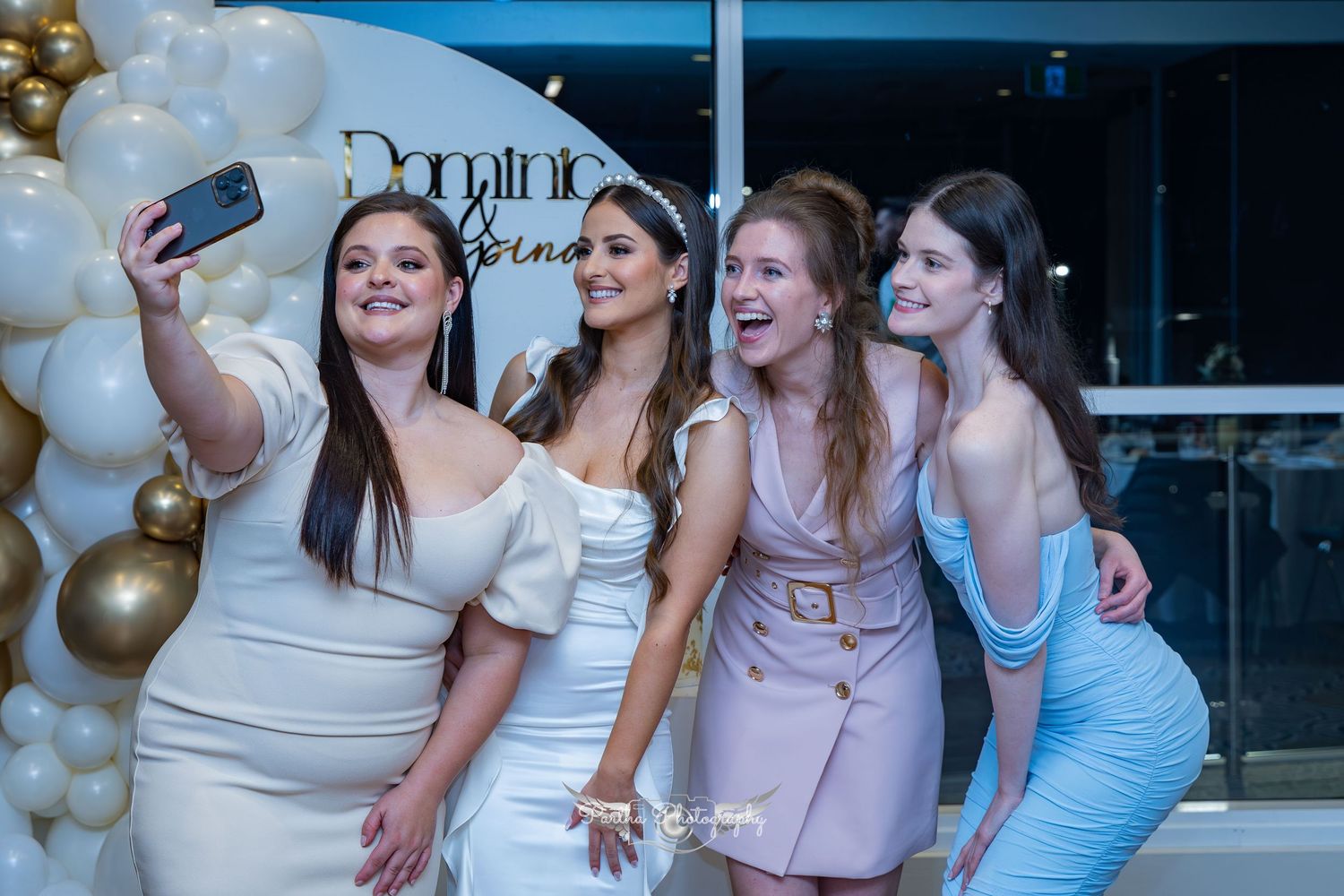 Group of friends taking selfie at engagement party with balloon decorations.