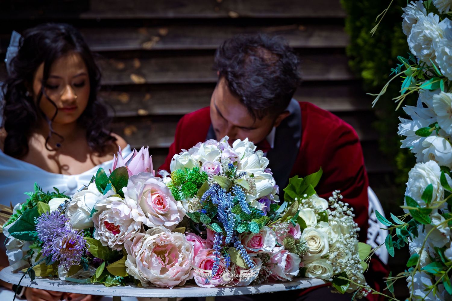 Close up of ornate wedding table display with pink and purple floral arrangements and candles.