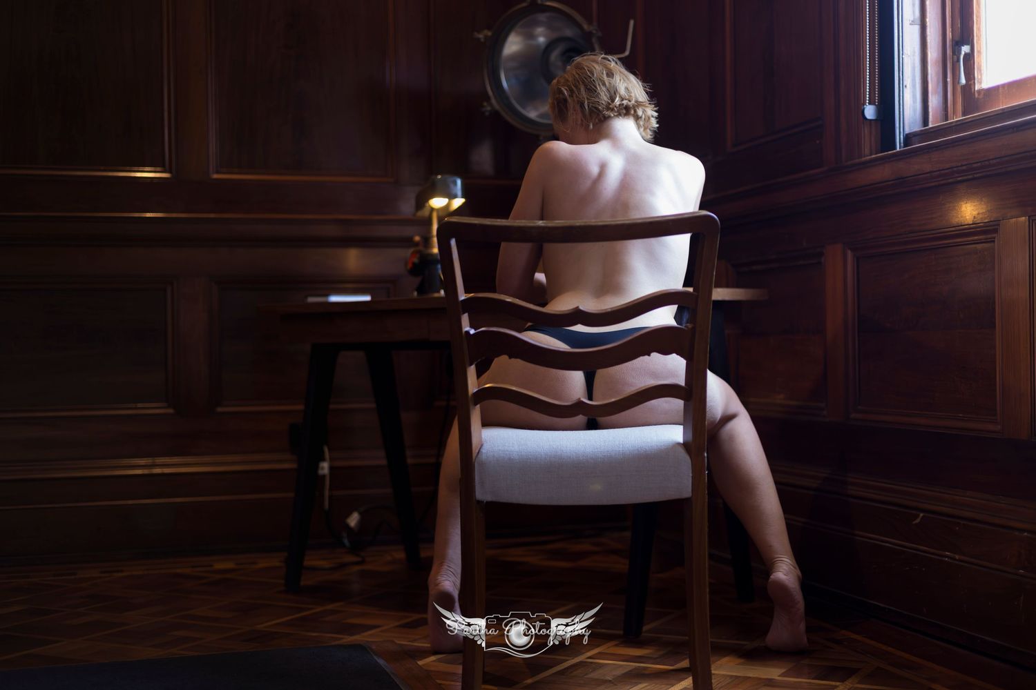 A person sits in a luxurious leather chair in a dimly lit room with dark wood paneled walls.