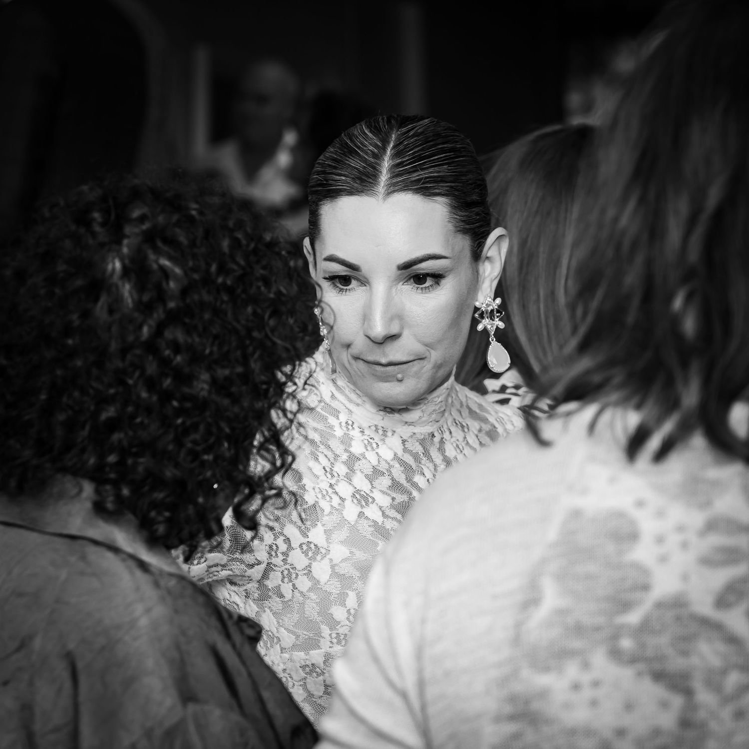 Black and white photo of someone amidst a crowd wearing an elegant dress with a textured ruffle neckline.
