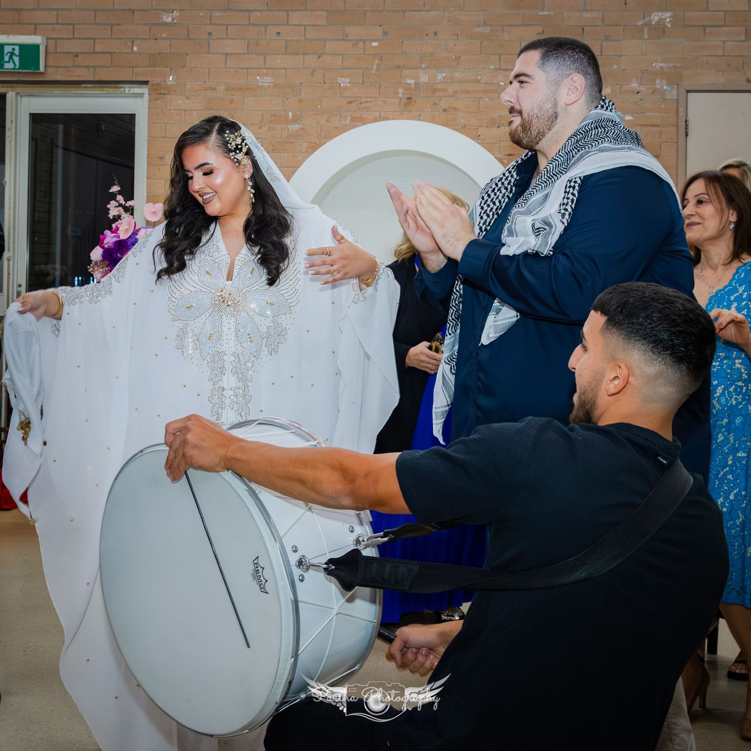 Wedding celebration with musicians playing drums while others dance and clap.