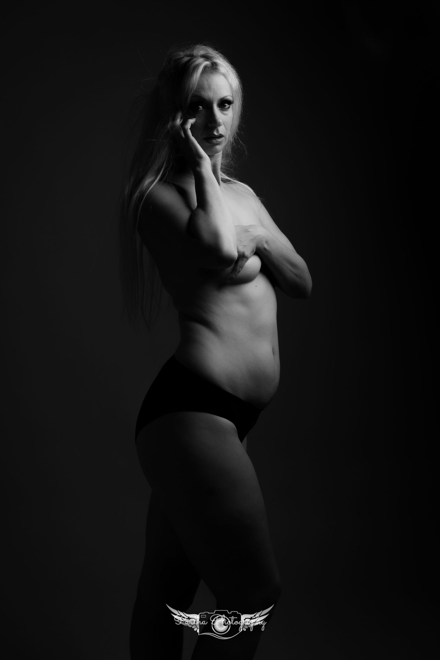 Dramatic black and white art nude portrait with moody lighting.