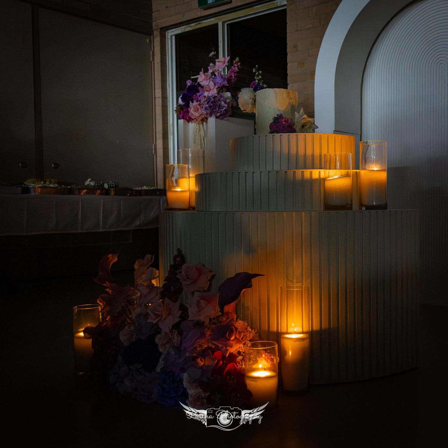 Romantic candlelit wedding decor with purple flowers and glowing lanterns in an evening setting.