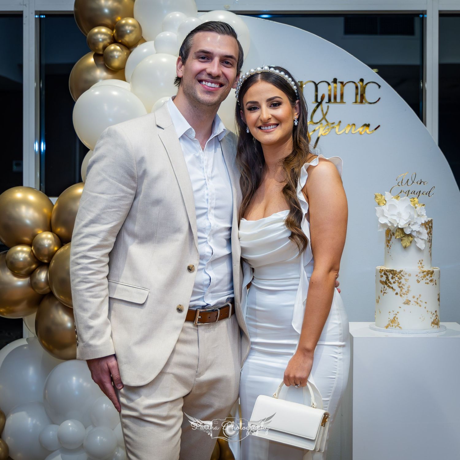 Wedding celebration with gold balloons, white cake, and elegant decor.