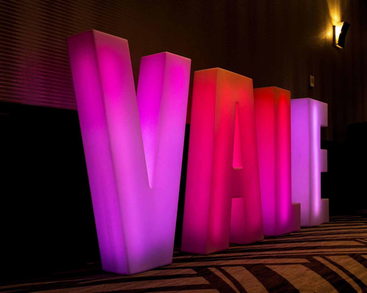 Large illuminated pink and purple letters spelling VALE stand as glowing 3D sculptures against a dark background.