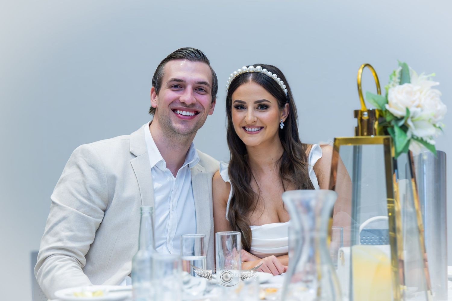 Elegant wedding reception setup with newlyweds seated at decorated table.