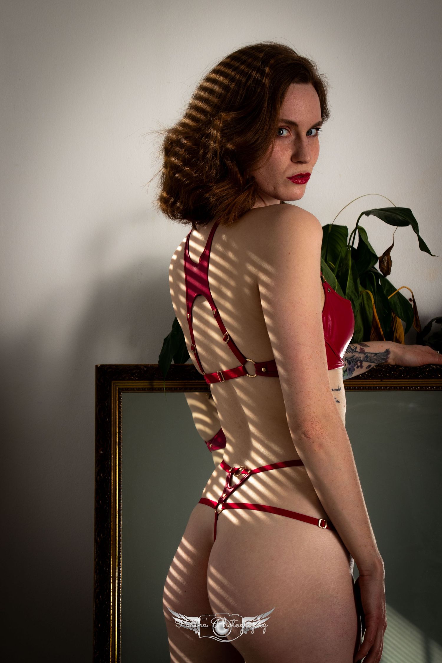 Vintage-style pin-up pose with red striped lingerie and window shadows.