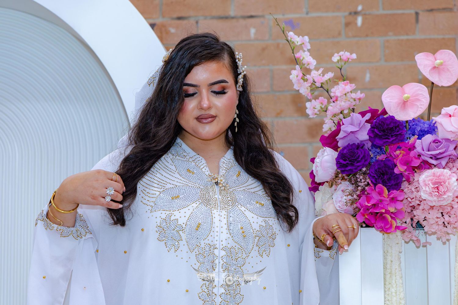 Close up of a bride in an embellished white dress with long dark hair and sparkly accessories.