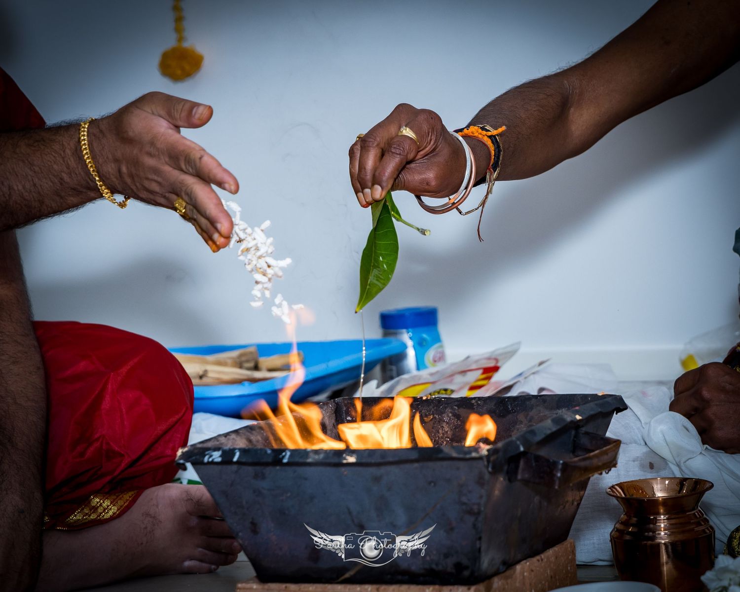 Hands performing a spiritual ritual with leaves and fire in a metal bowl during a sacred ceremony.