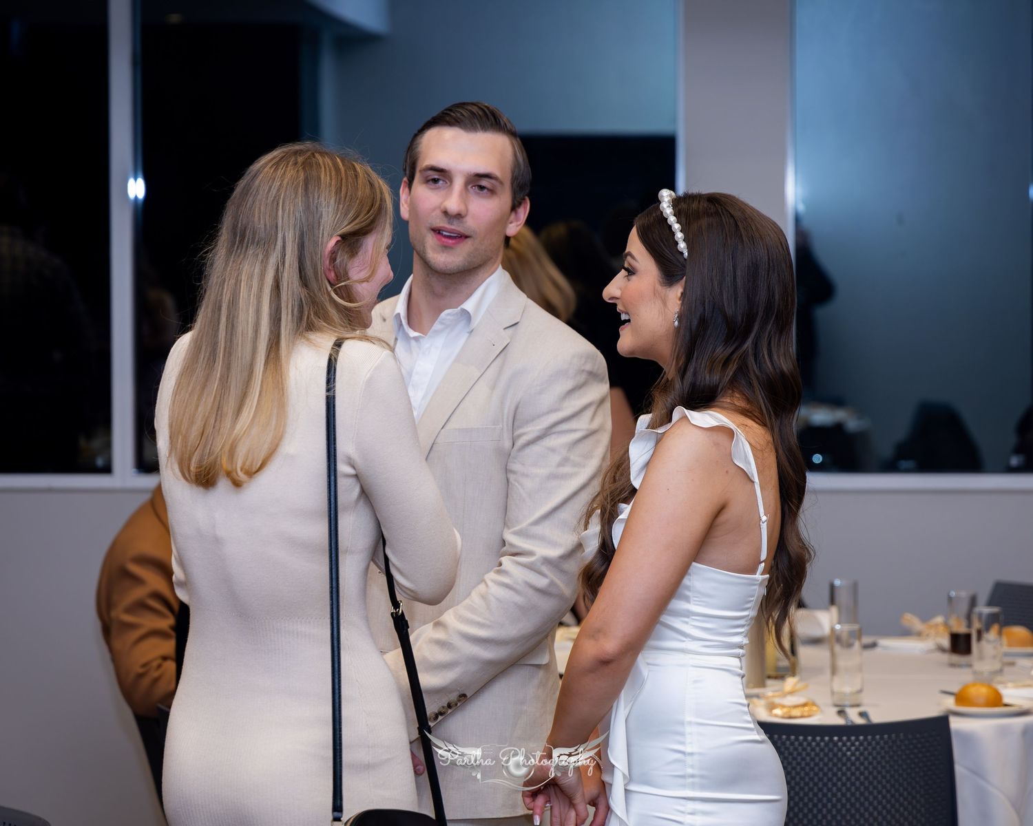 Wedding reception guests chatting in formal attire.