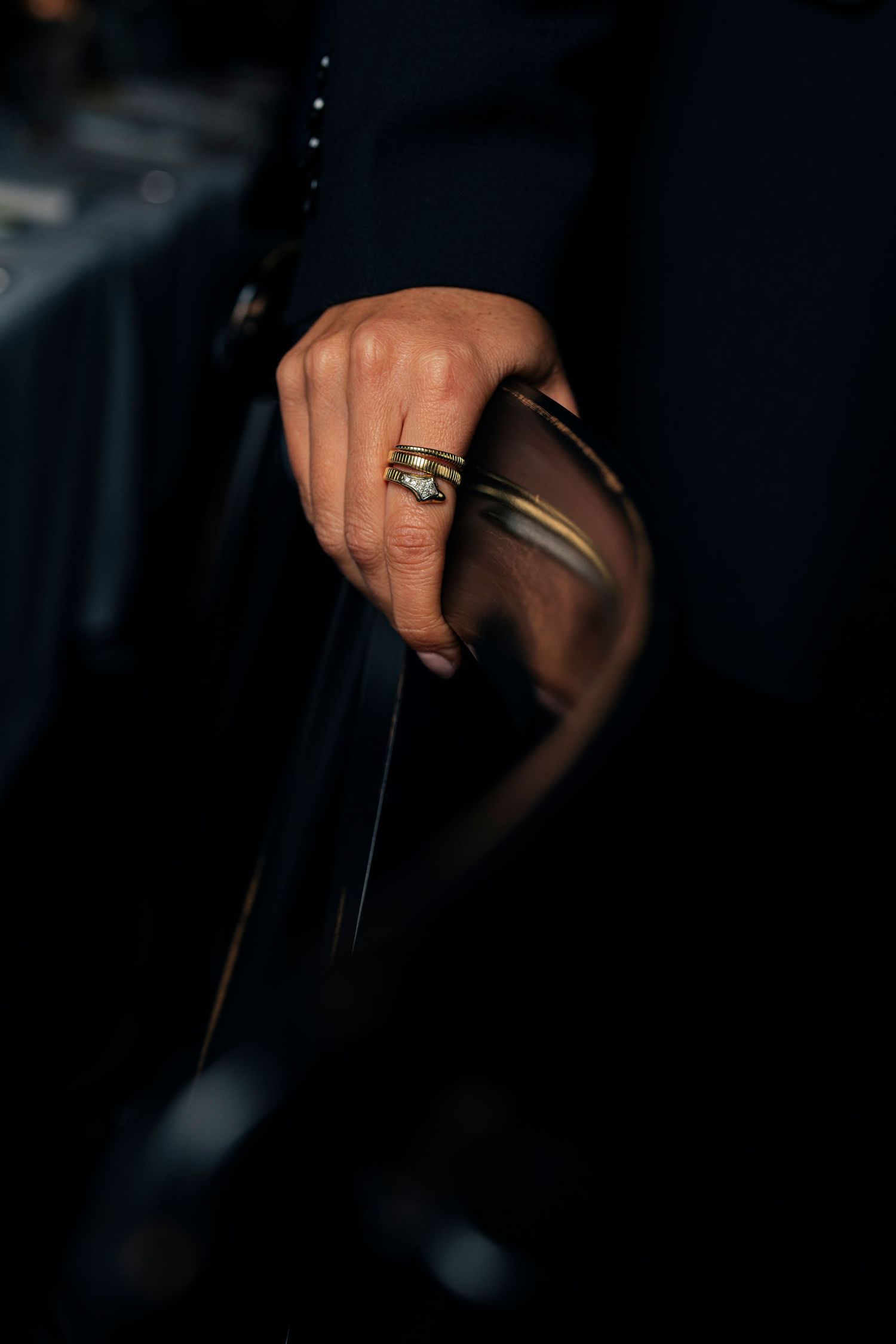 Close-up shot of hand with a gold ring in low light conditions.