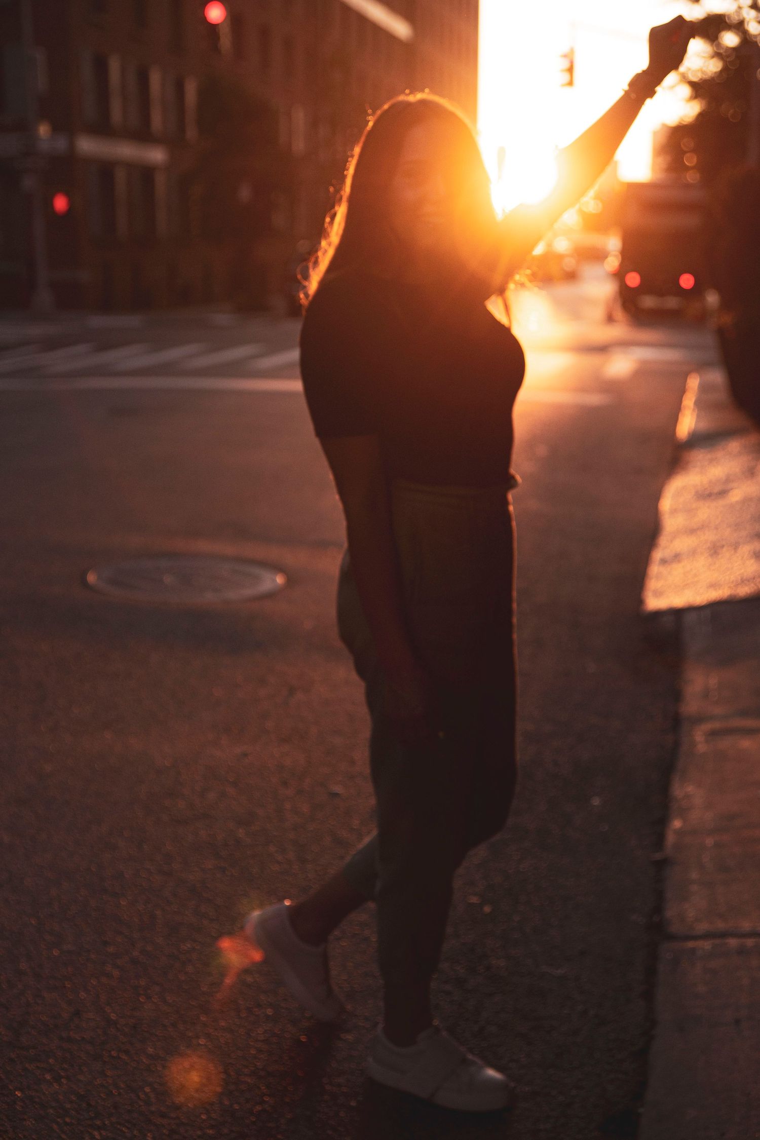 Silhouette of person posing on street during golden hour sunset.
