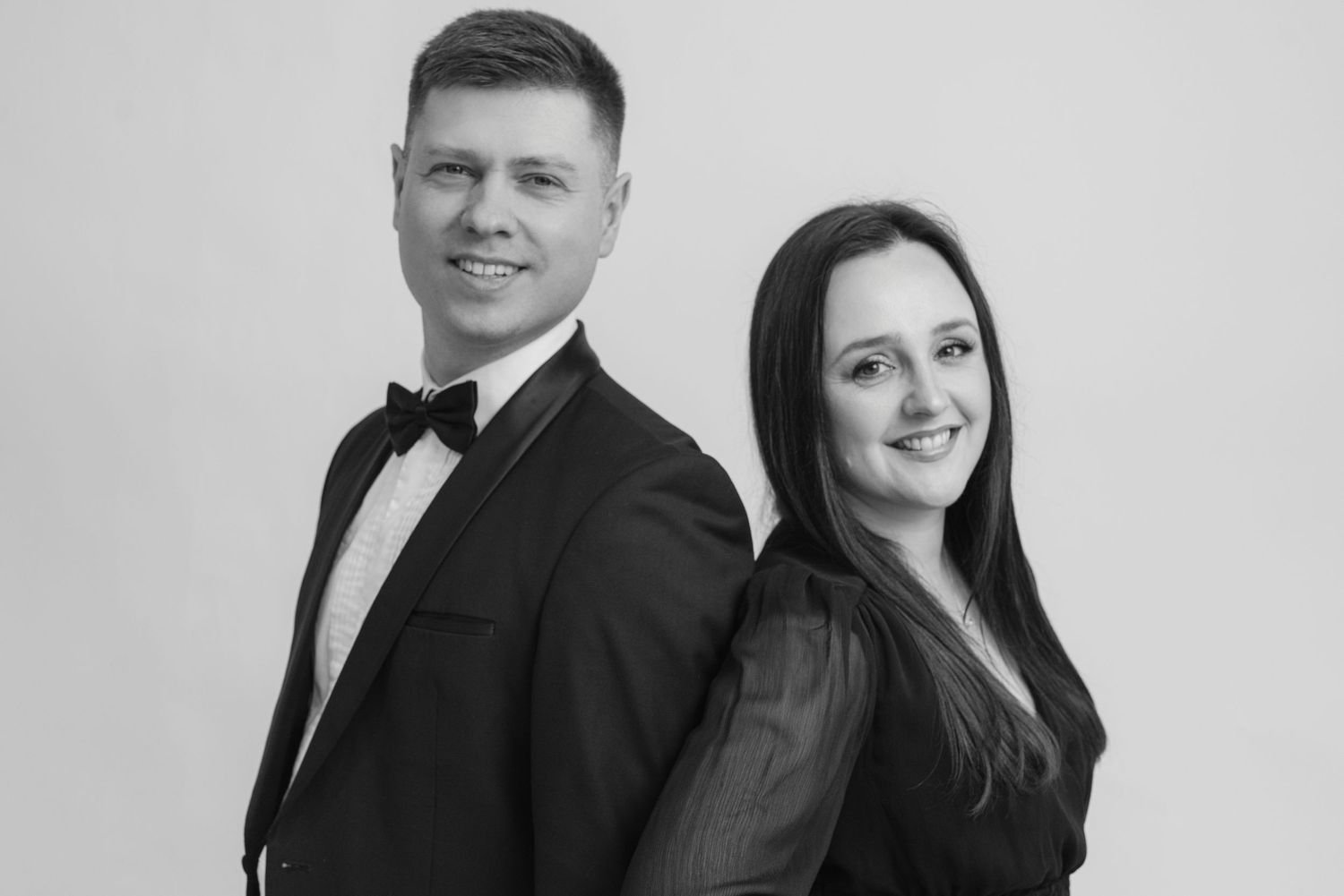 A couple in formal attire poses for black and white portrait photos.