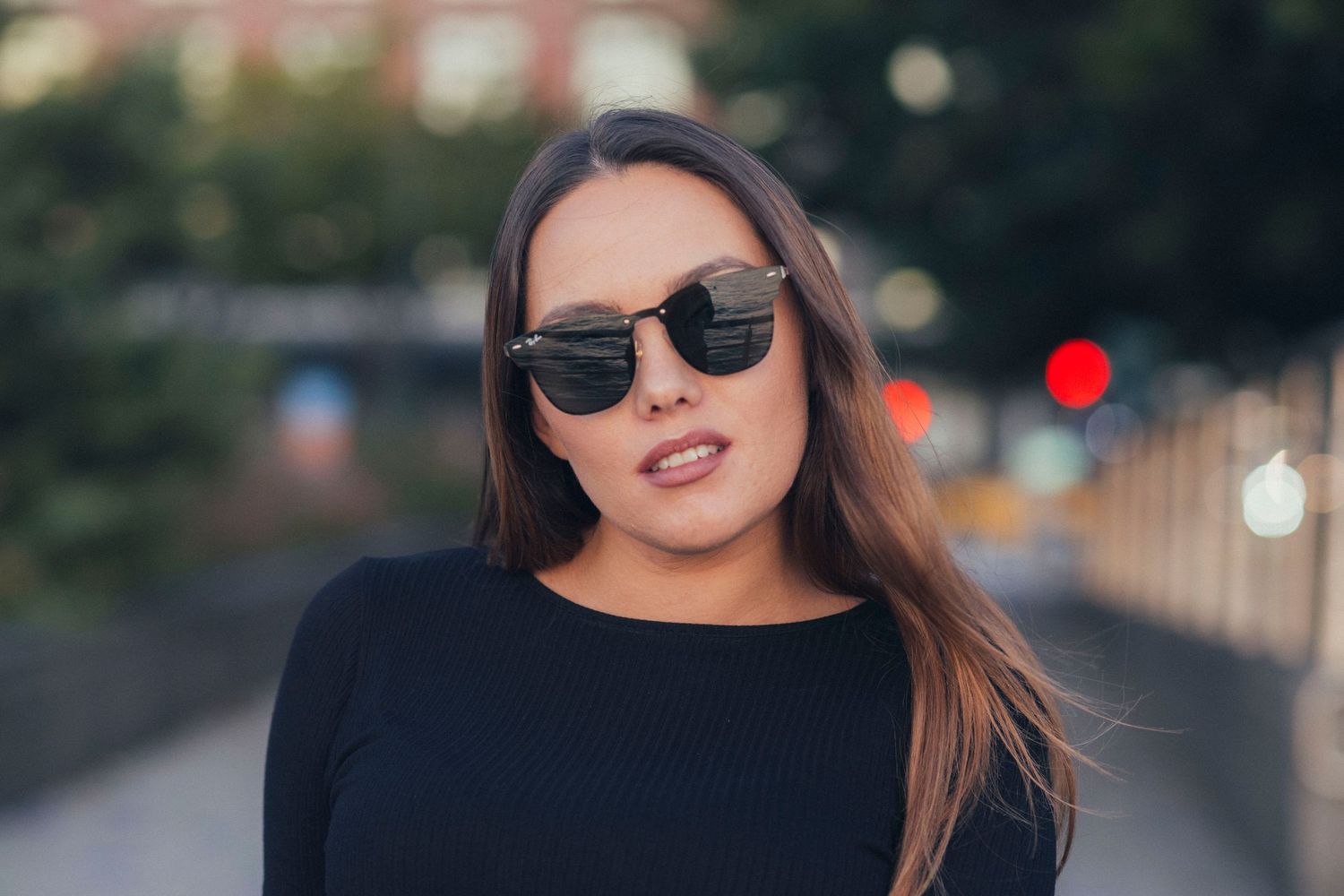 Urban fashion portrait of woman in black top wearing trendy sunglasses.