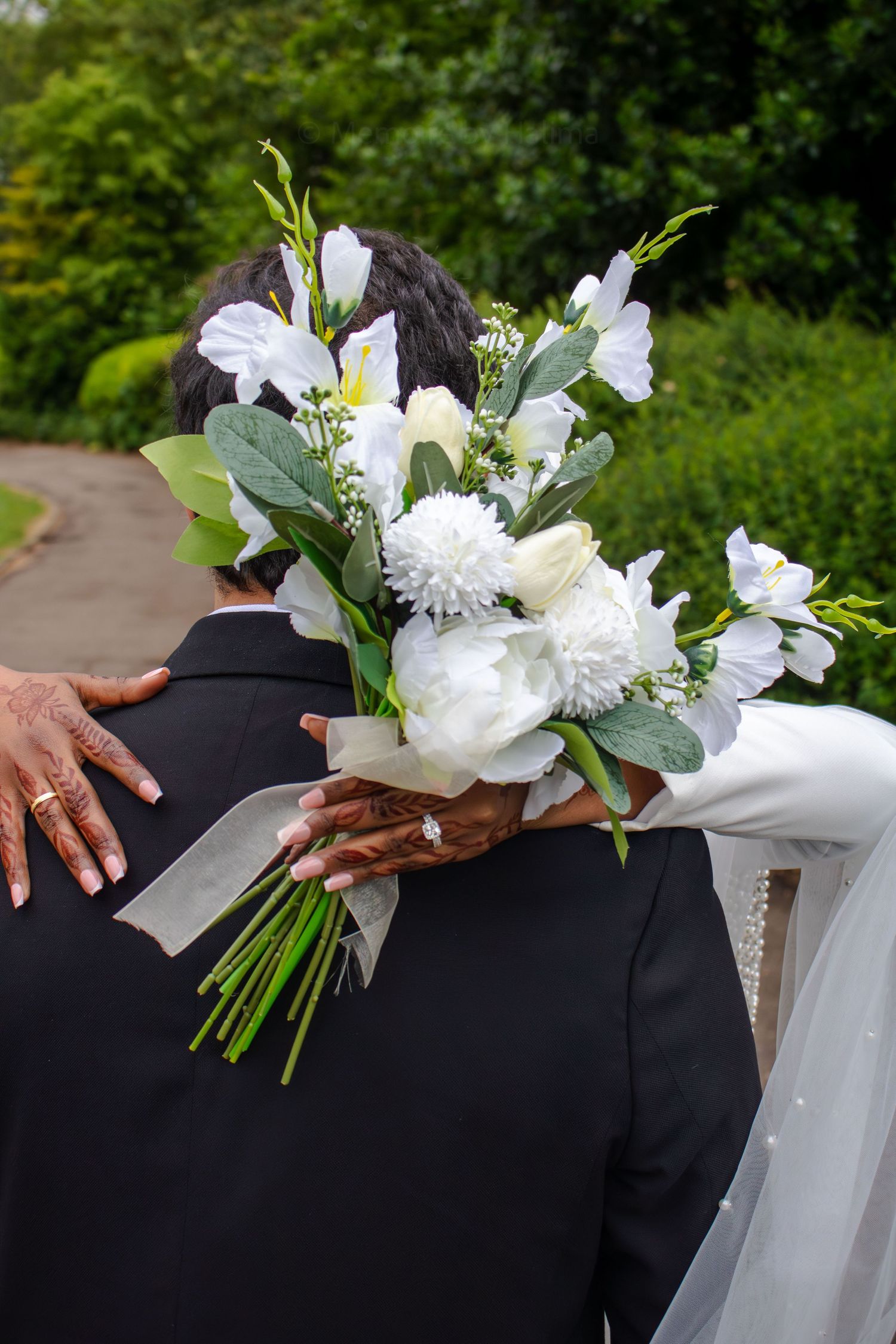 A series of wedding photos showing close-up details of a couple embracing with white floral bouquet against a dark suit.