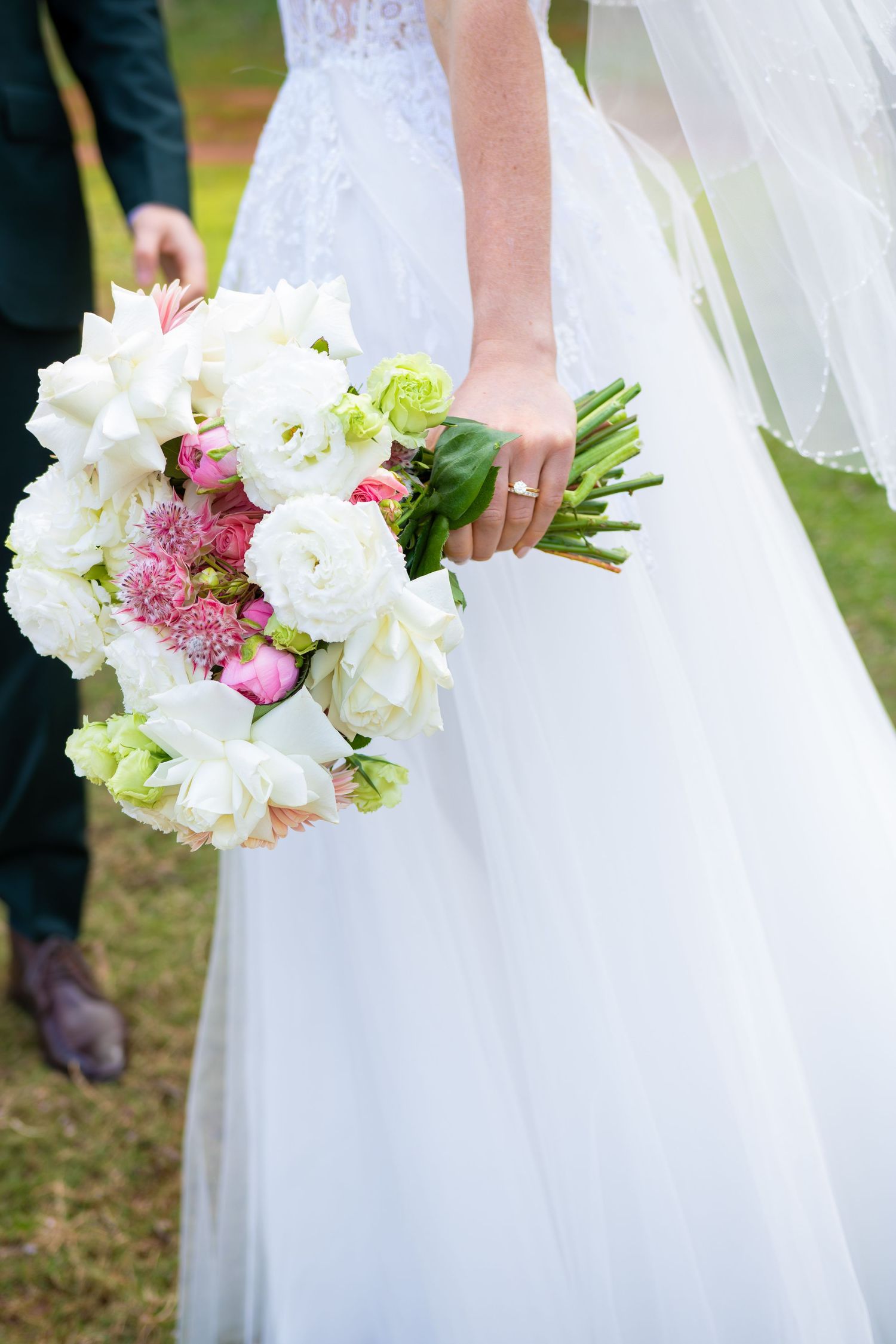 A white wedding dress and floral bouquet featuring white peonies and pink accents are shown in detail.