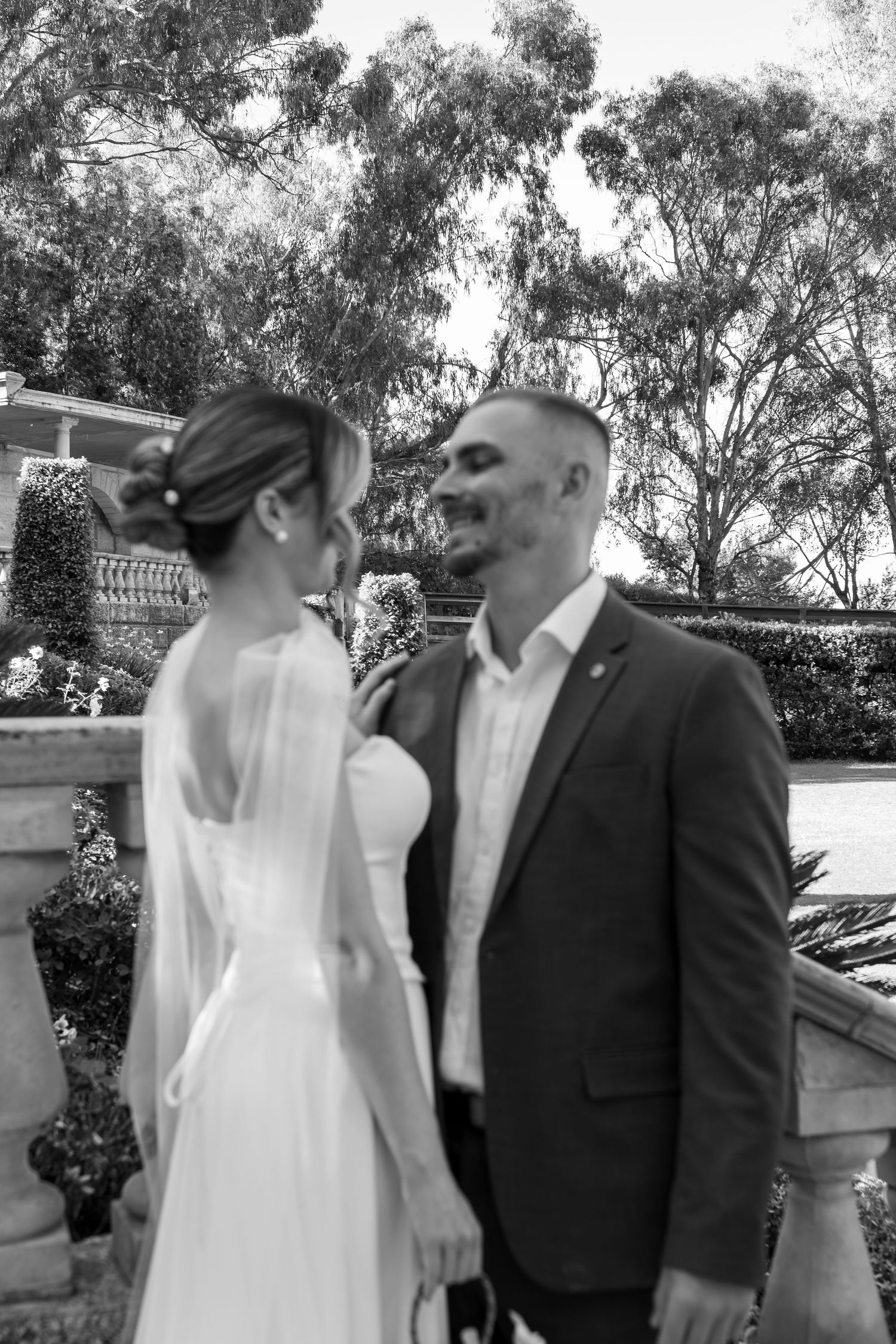 A wedding couple shares intimate moments while posing for romantic photos in an outdoor garden setting.