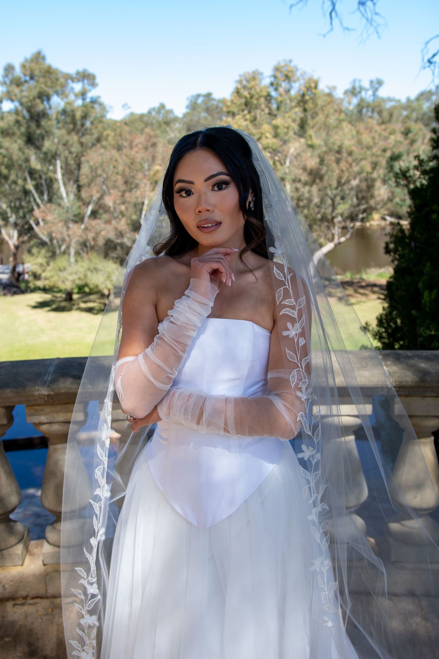 A bride in a white wedding gown and veil poses outdoors against a natural landscape backdrop in a series of photos.