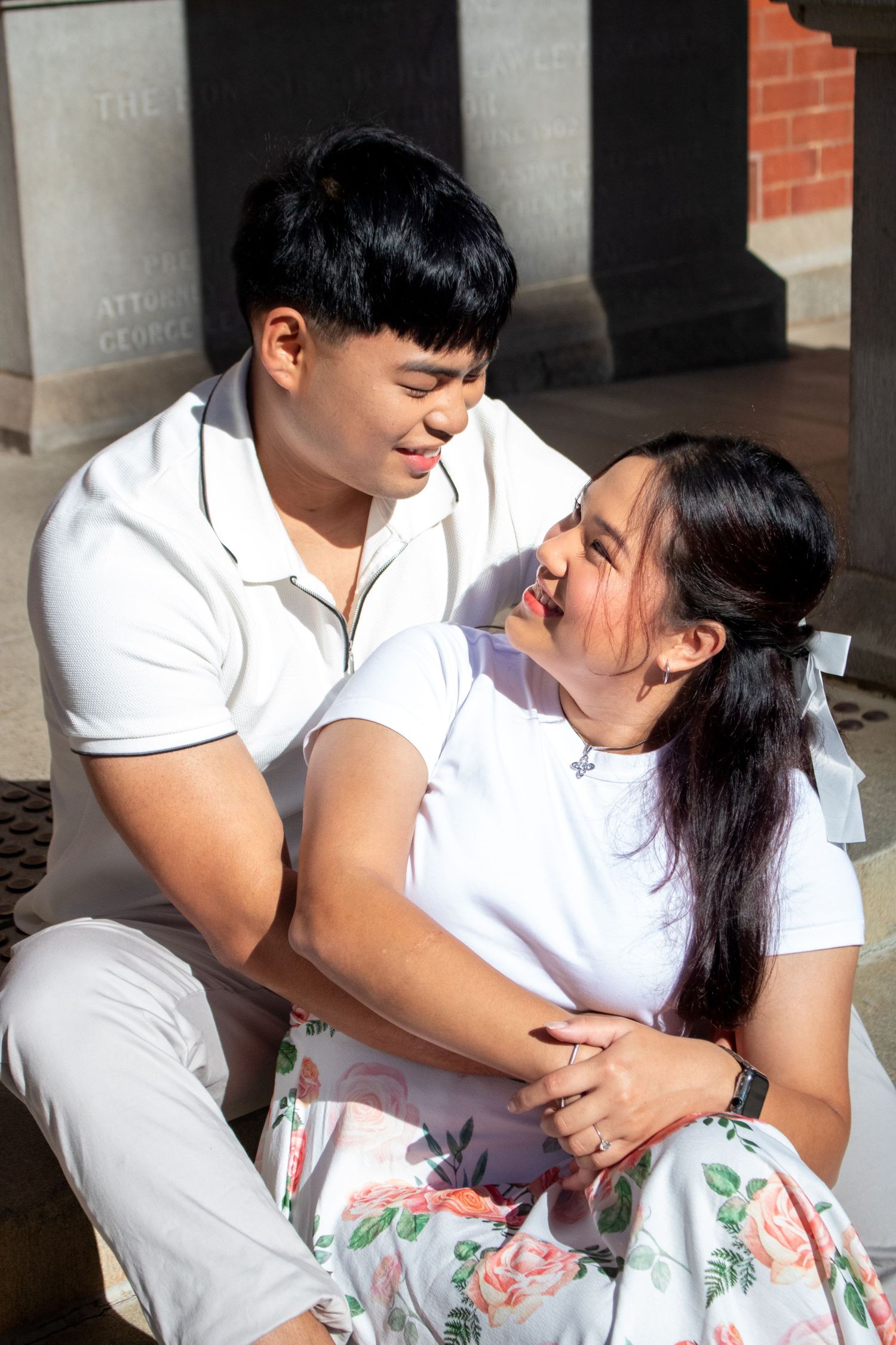 Couple in matching white outfits sharing an intimate moment outdoors.