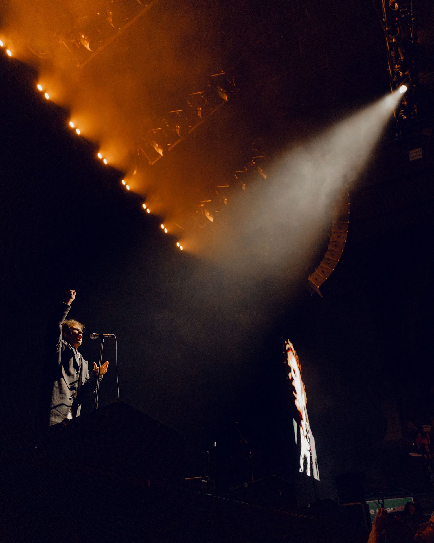 Concert stage lighting creates dramatic silhouettes of performers in a smoky atmosphere during a live performance.