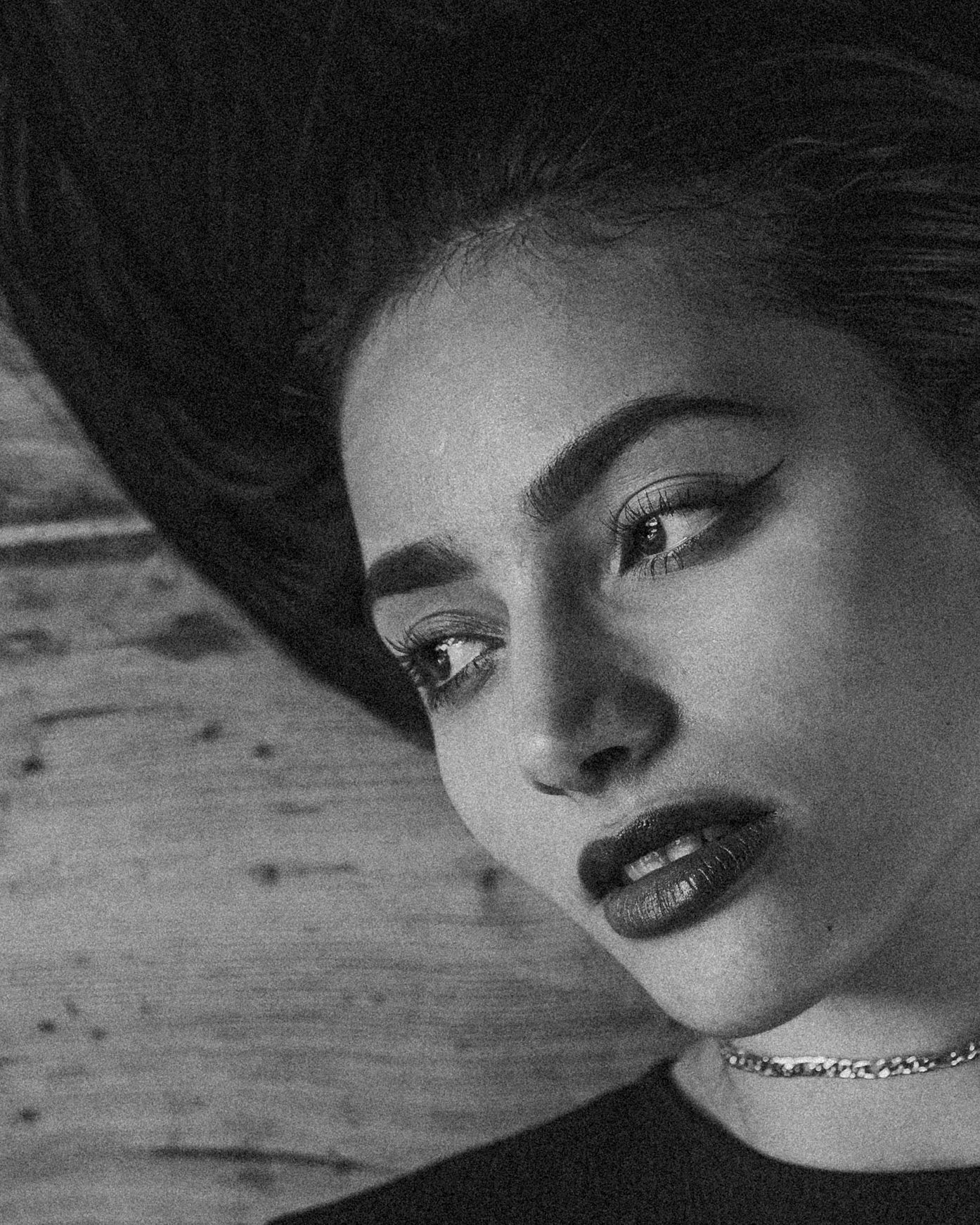 Dramatic black and white portrait with dark lipstick and choker against wooden background.