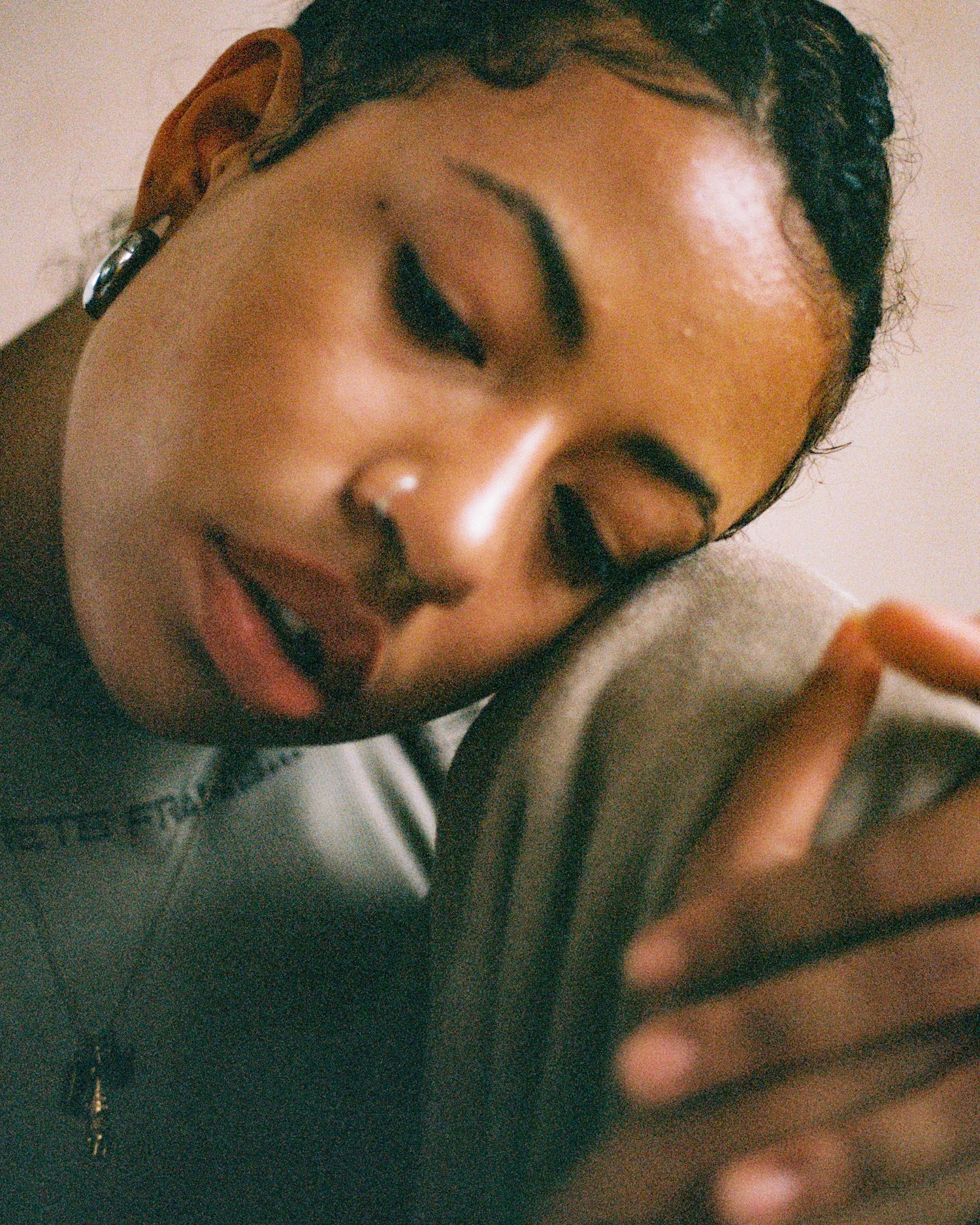 Close-up portrait showing a peaceful expression with eyes closed in soft lighting.