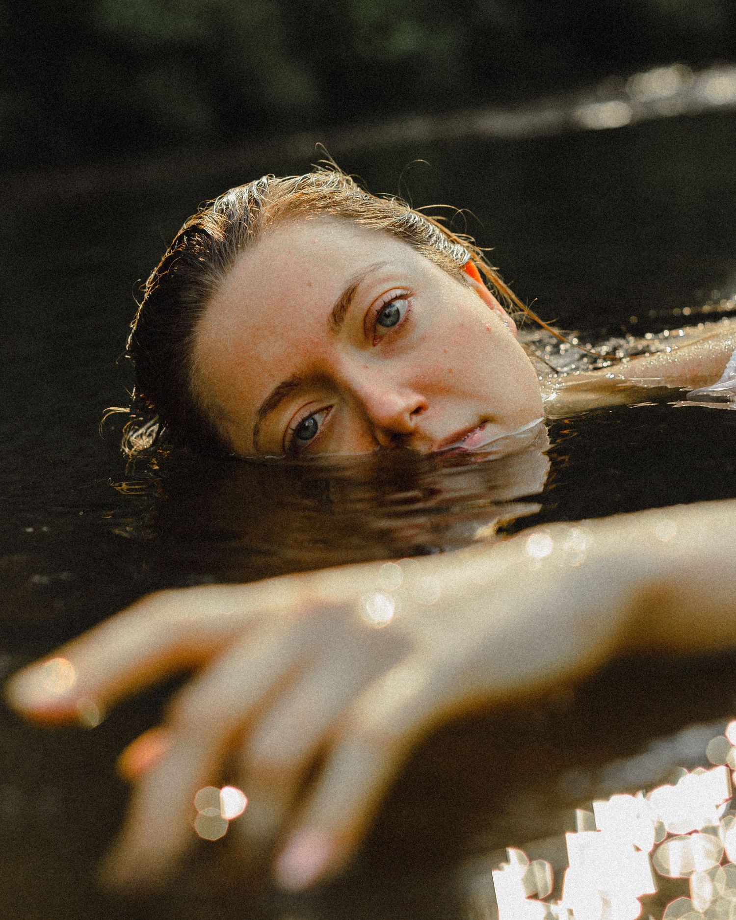 Ethereal underwater photography with soft natural lighting and reflective water surface.