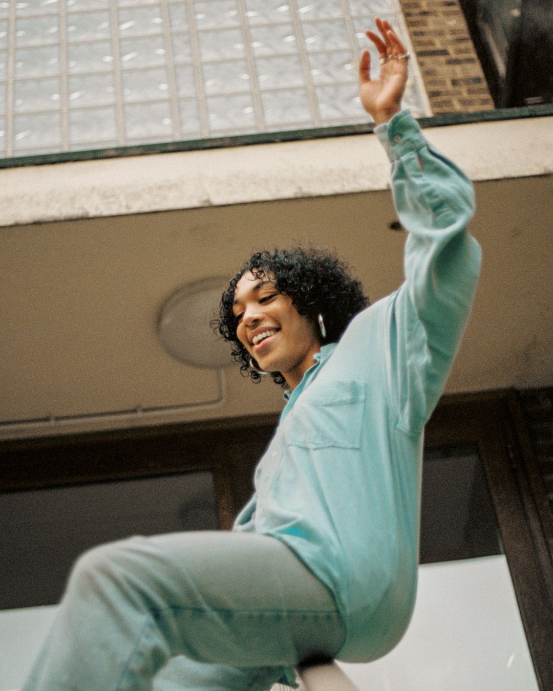 Playful fashion shot showing joyful pose in matching mint green outfit on building steps.