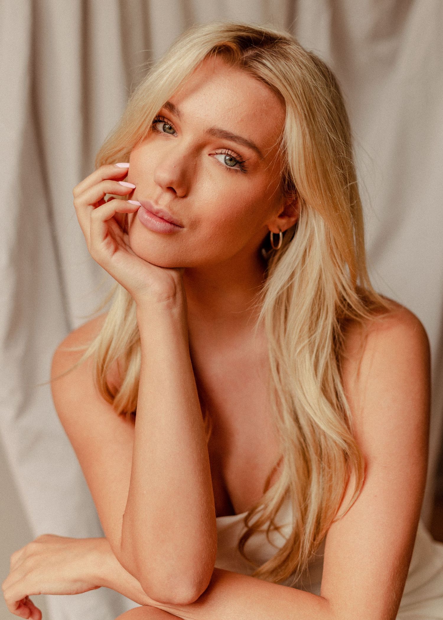 Lifestyle portrait series with relaxed poses against draped fabric.
