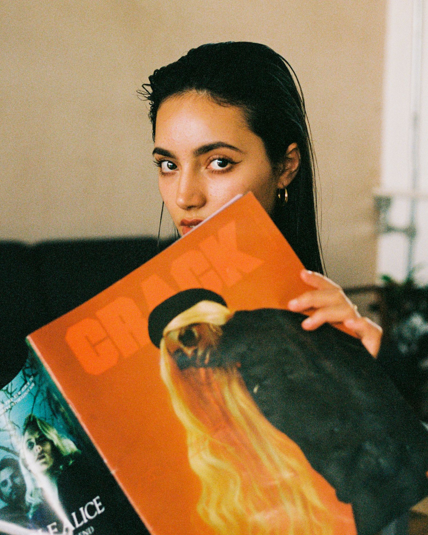 A moody portrait holding an orange book cover in dramatic lighting.
