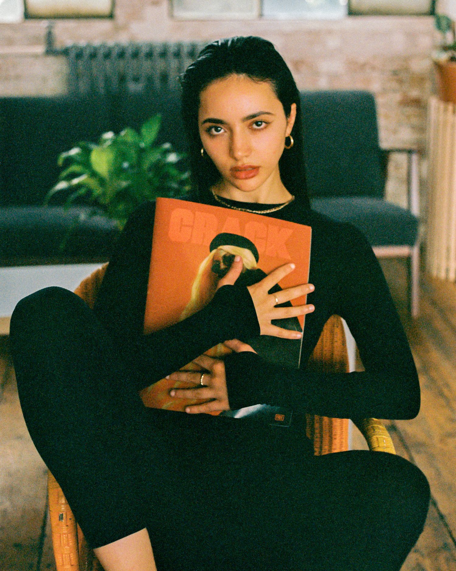Indoor portrait in all black attire holding an orange book.
